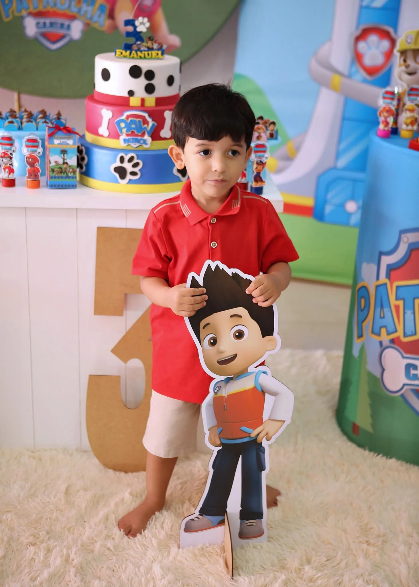 Menino de camisa vermelha ao lado de figura de desenho animado, em festa infantil.