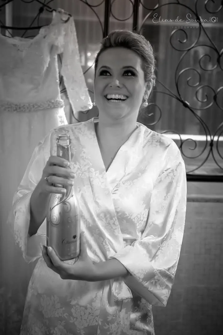 Noiva de robe sorrindo durante a preparação, em preto e branco.