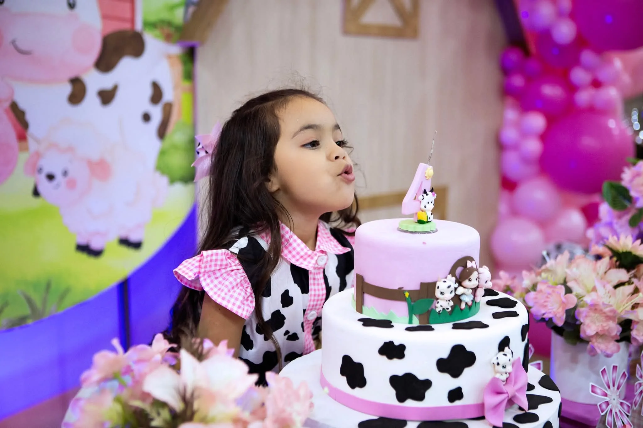 Menina soprando a vela do bolo em festa com tema de fazenda.