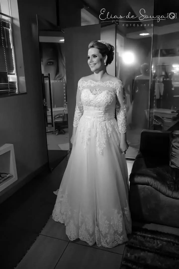 Noiva de vestido de renda em corredor, em preto e branco.
