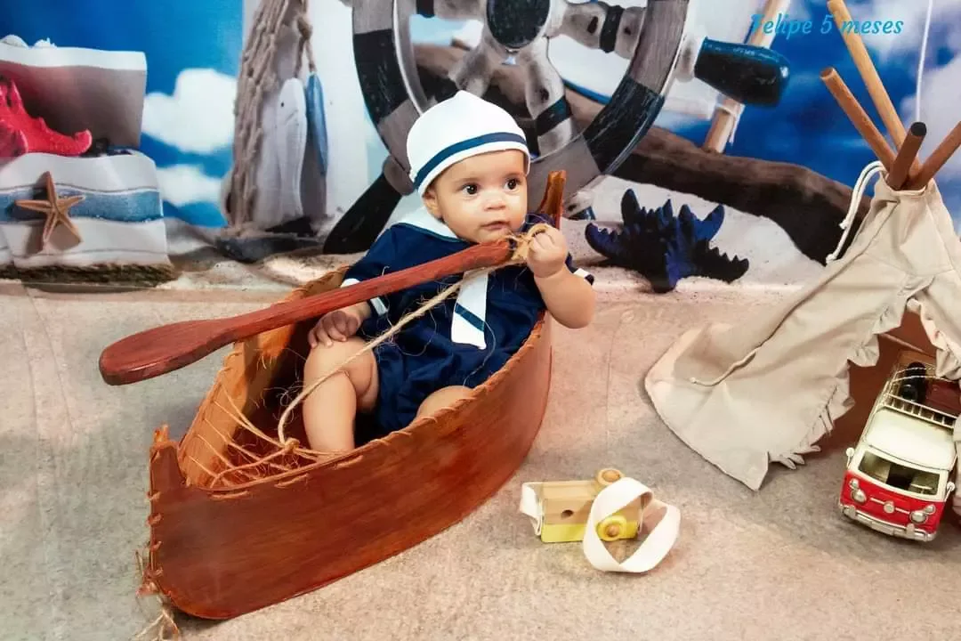 Bebê de 5 meses de roupa de marinheiro em barquinho com remo.