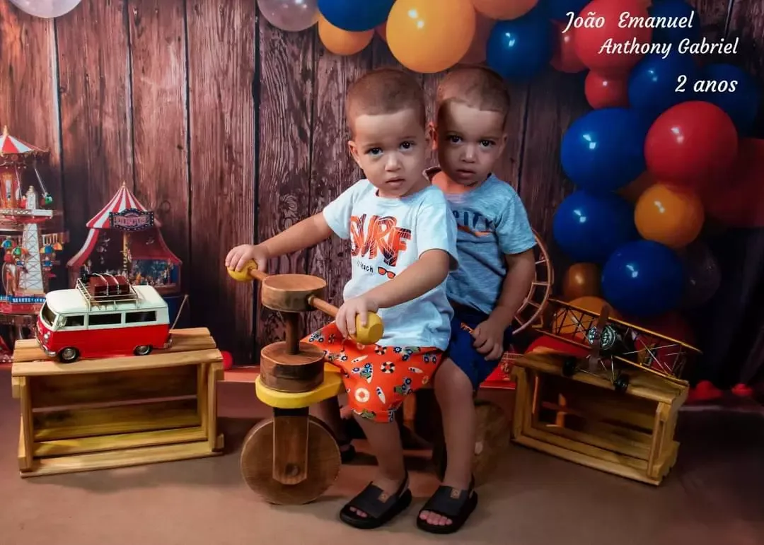 Duas crianças de 2 anos brincando com carrinho e balões coloridos.